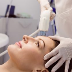 Doctor giving cosmetic treatment to female patient at clinic