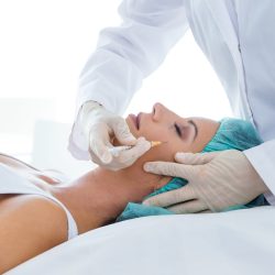 Portrait of beautiful young woman getting botox cosmetic injection in her face.
