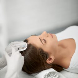 Side view of young cute brunette woman on procedure for improvements hair condition. Concept of different procedure for hair restoration in professional beauty salon.