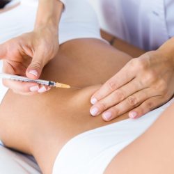 Portrait of surgeon making injection into female body. Liposuction concept.